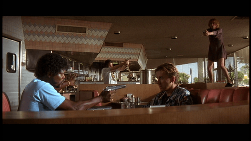 Duelo do tipo "mexican standoff" em cena do filme Pulp Fiction
